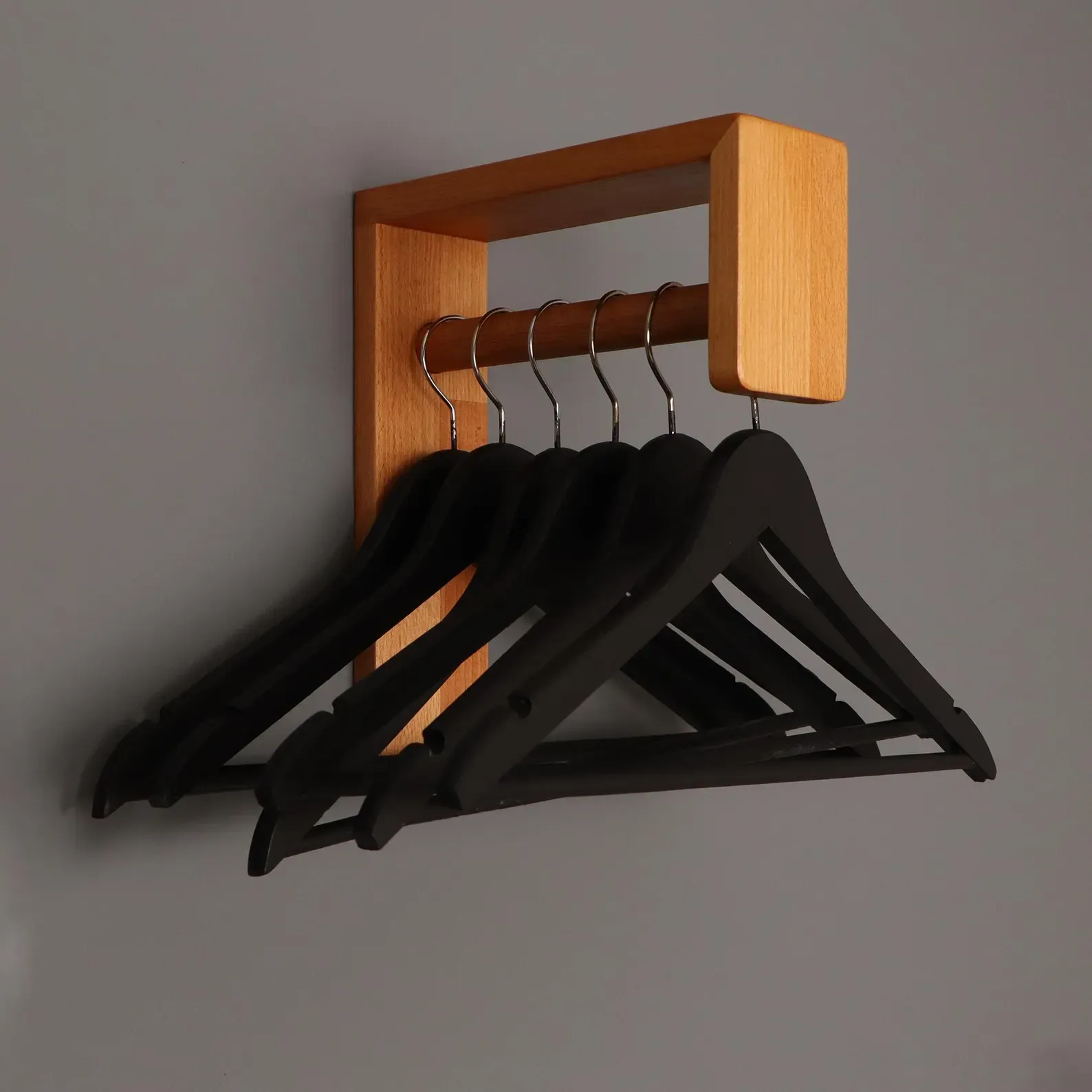The wooden tone wall hanger for hallway use made from wood supports coat hanging with simple storage design